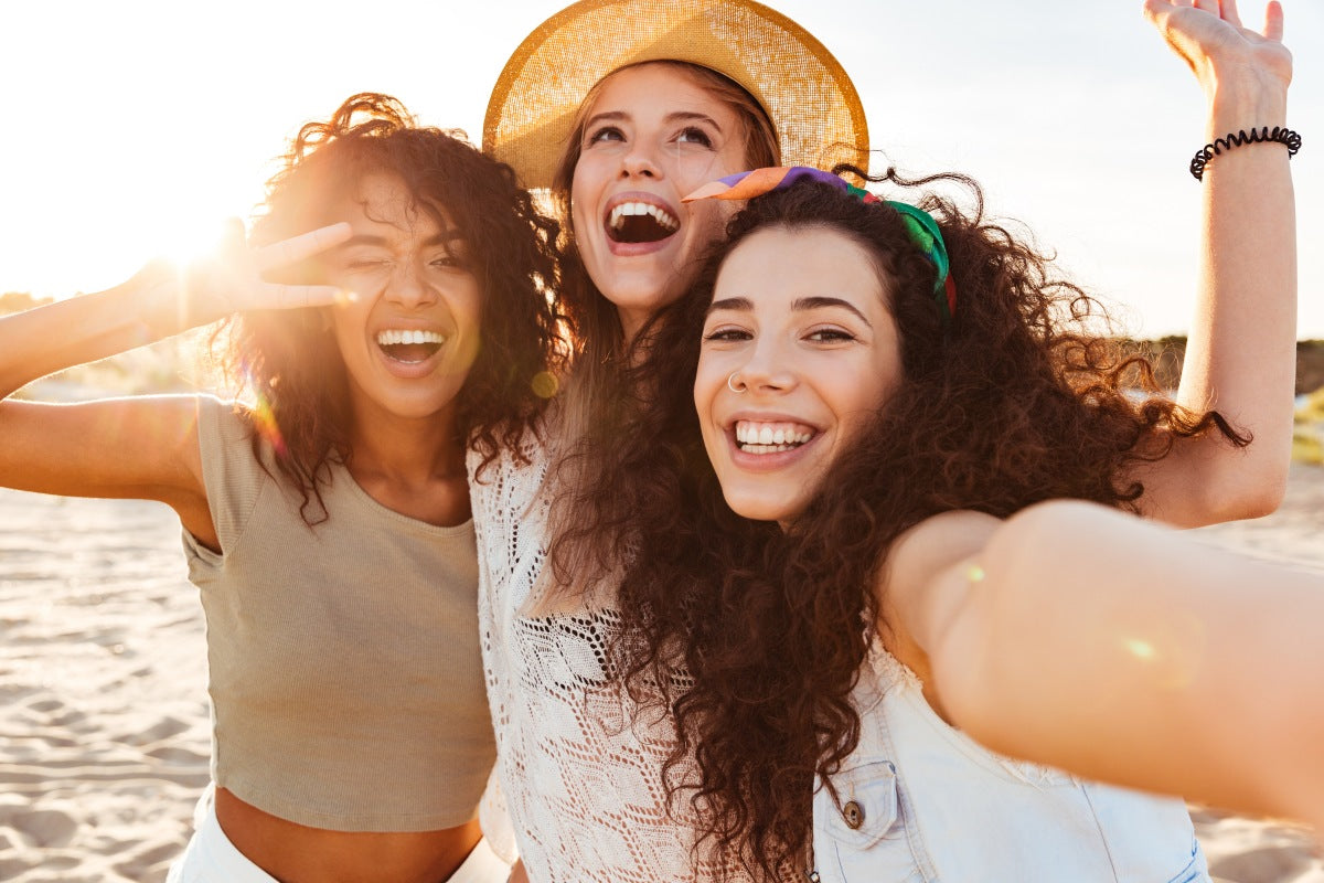 Happy girls at the beach wondering what to wear under a swimsuit for comfort and confidence.
